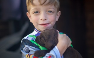 Albie, diagnosed with LAL-D as an infant, holding a puppy